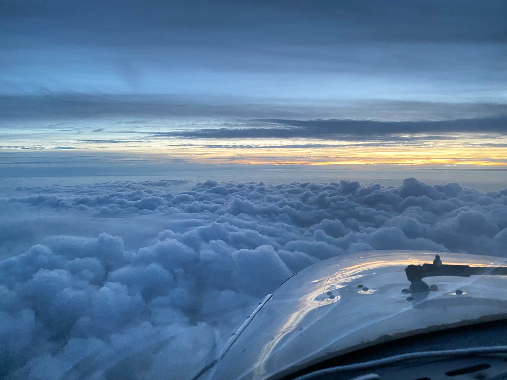 Dusk seen from PA31 cockpit over a bed of clouds